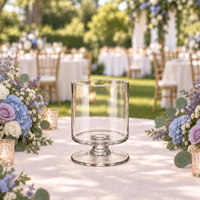 Elegant outdoor wedding table setting with clear glass centerpiece and floral arrangements