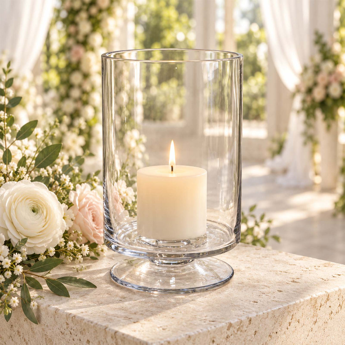 Glass hurricane candle holder with lit pillar candle and floral wedding décor