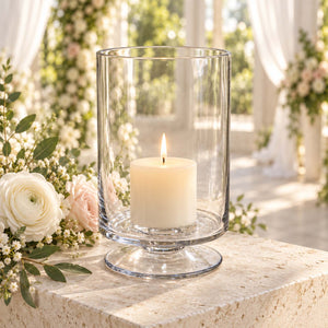 Glass hurricane candle holder with lit pillar candle and floral wedding décor