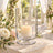 Glass hurricane candle holder with lit pillar candle and floral wedding décor