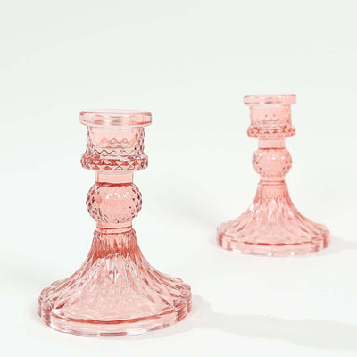 Pink crystal candle holders on a plain backdrop.