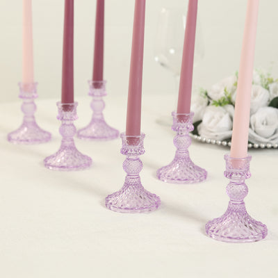 Purple glass candle holders with tapered candles arranged elegantly.