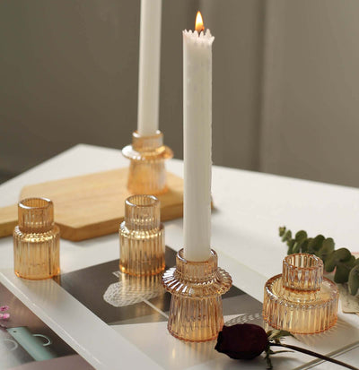 Elegant amber glass candle holders with white candles on a stylish tabletop.