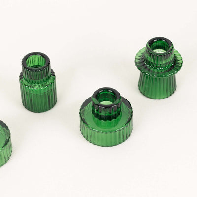 Green glass candle holders in various sizes arranged on a plain background.