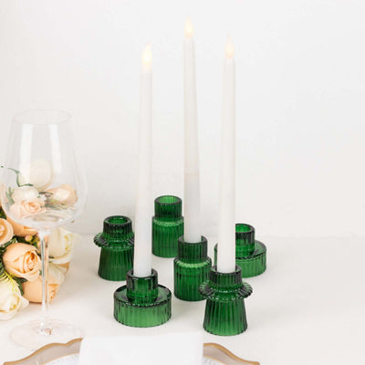 Green glass candle holders with white candles and floral accents.