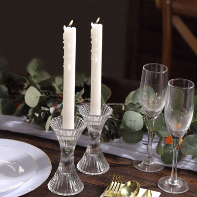 Elegant crystal candle holders with tall white candles on a dining table.