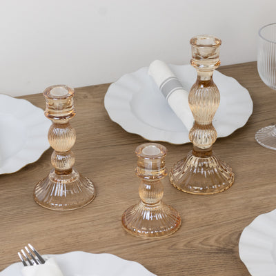 Elegant glass candle holders in various heights on a wooden table.
