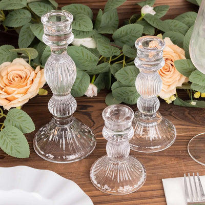 Set of three elegant glass candlesticks with ribbed design.