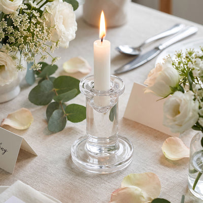Elegant wedding table centerpiece with lit candle, white roses, and greenery