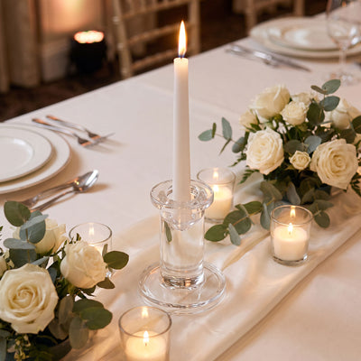 Elegant wedding table centerpiece with candles, white roses, and greenery