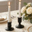 Elegant black candle holders with lit taper candles and white roses on a table.