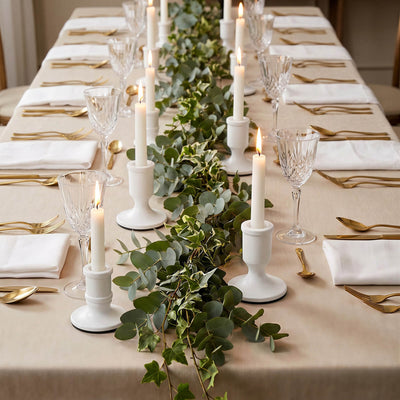 Elegant candlelit dining table with eucalyptus greenery and gold flatware