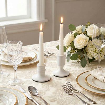 Elegant white candlelit table setting with roses, gold-rimmed plates, and glassware