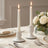Elegant white taper candles with roses on a wedding table setting
