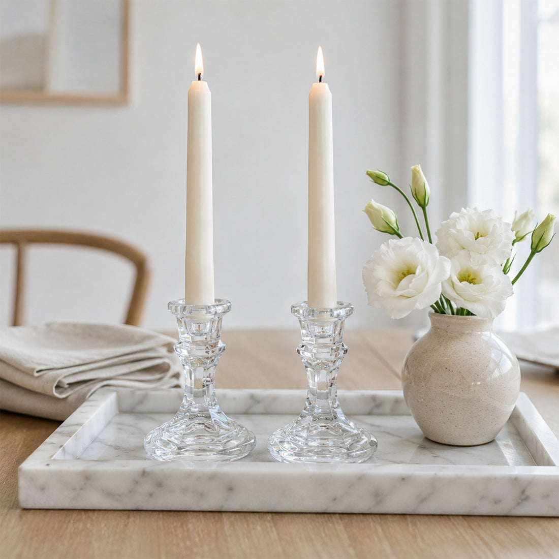 Minimalist dining table decor with lit candles and white flowers in a vase
