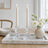 Minimalist dining table decor with lit candles and white flowers in a vase