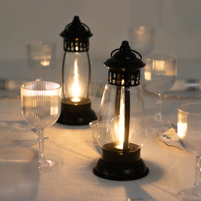 Black lanterns glowing on a table set with elegant glassware.
