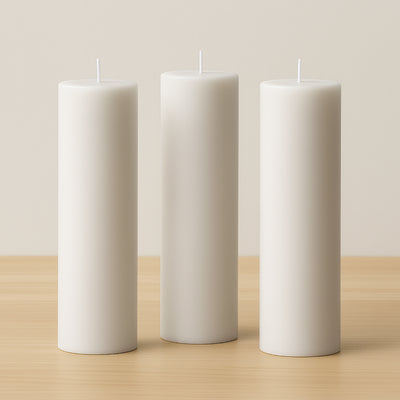 Three white pillar candles on a wooden surface.