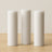 Three white pillar candles on a wooden surface.