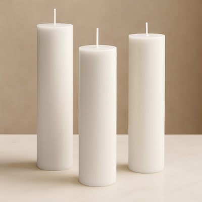 Three elegant white pillar candles in varying heights on a neutral surface.