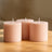 Three pink candles on a wooden table in soft natural light.