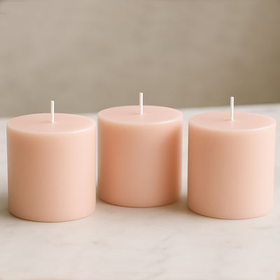 Pink pillar candles in varying heights on a marble surface.