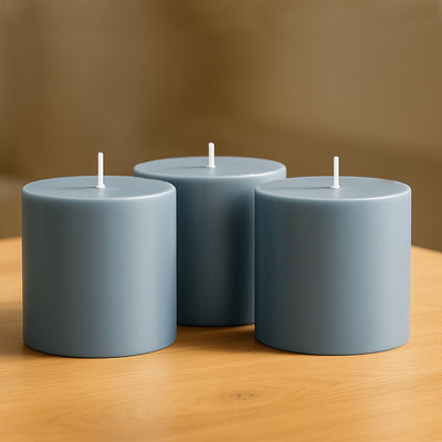 Three blue cylindrical candles on a wooden table.