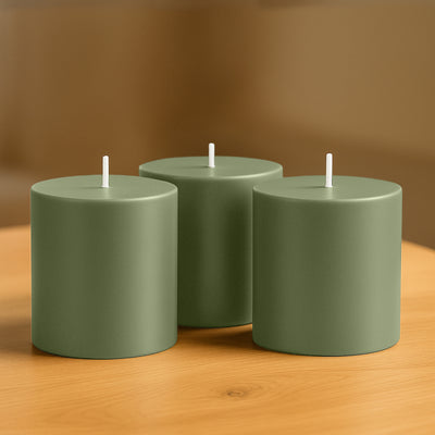 Set of three green cylindrical candles on a wooden surface.
