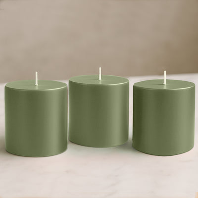 Green cylindrical candles in varying heights on a marble surface.