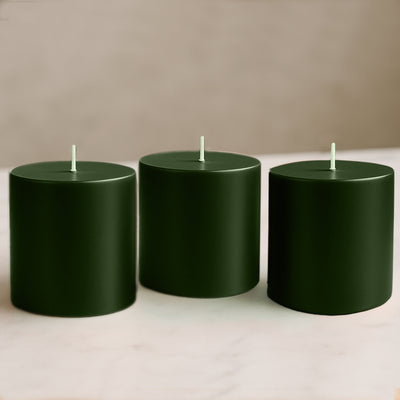 Green cylindrical candles in varying heights on a neutral surface.