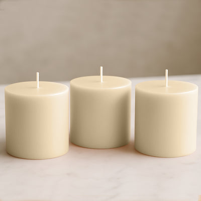 Set of three cream pillar candles on a marble surface.