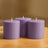 Purple cylindrical candles arranged on a wooden surface.
