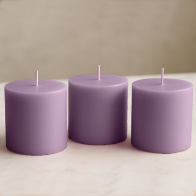 Three lavender pillar candles on a marble surface.