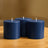 Three navy blue candles on a wooden table.