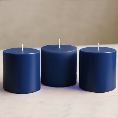 Set of three navy blue candles on a marble surface.