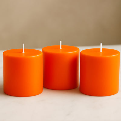 Three vibrant orange candles in a studio-style isolation shot.