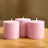 Pink decorative candles in various heights on a wooden surface.