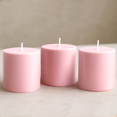 Set of three pink candles on a marble surface.