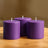Purple cylindrical candles arranged on a wooden surface.