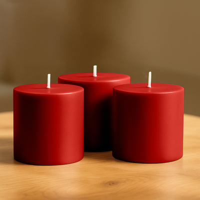 Three red candles arranged on a wooden table.