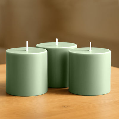 Three green cylindrical candles on a wooden table.
