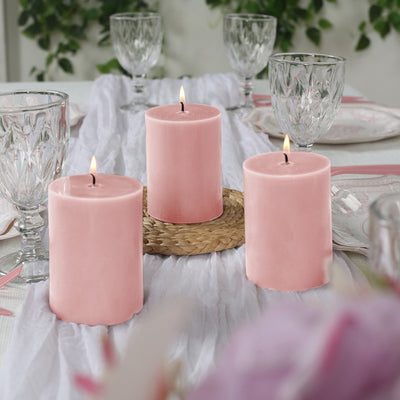 Pink candles on a table setting with glassware and floral accents.