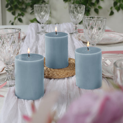 Blue pillar candles arranged on a dining table with crystal glassware and floral decor.