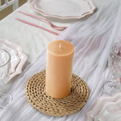 Peach pillar candle on a woven placemat with elegant dinnerware
