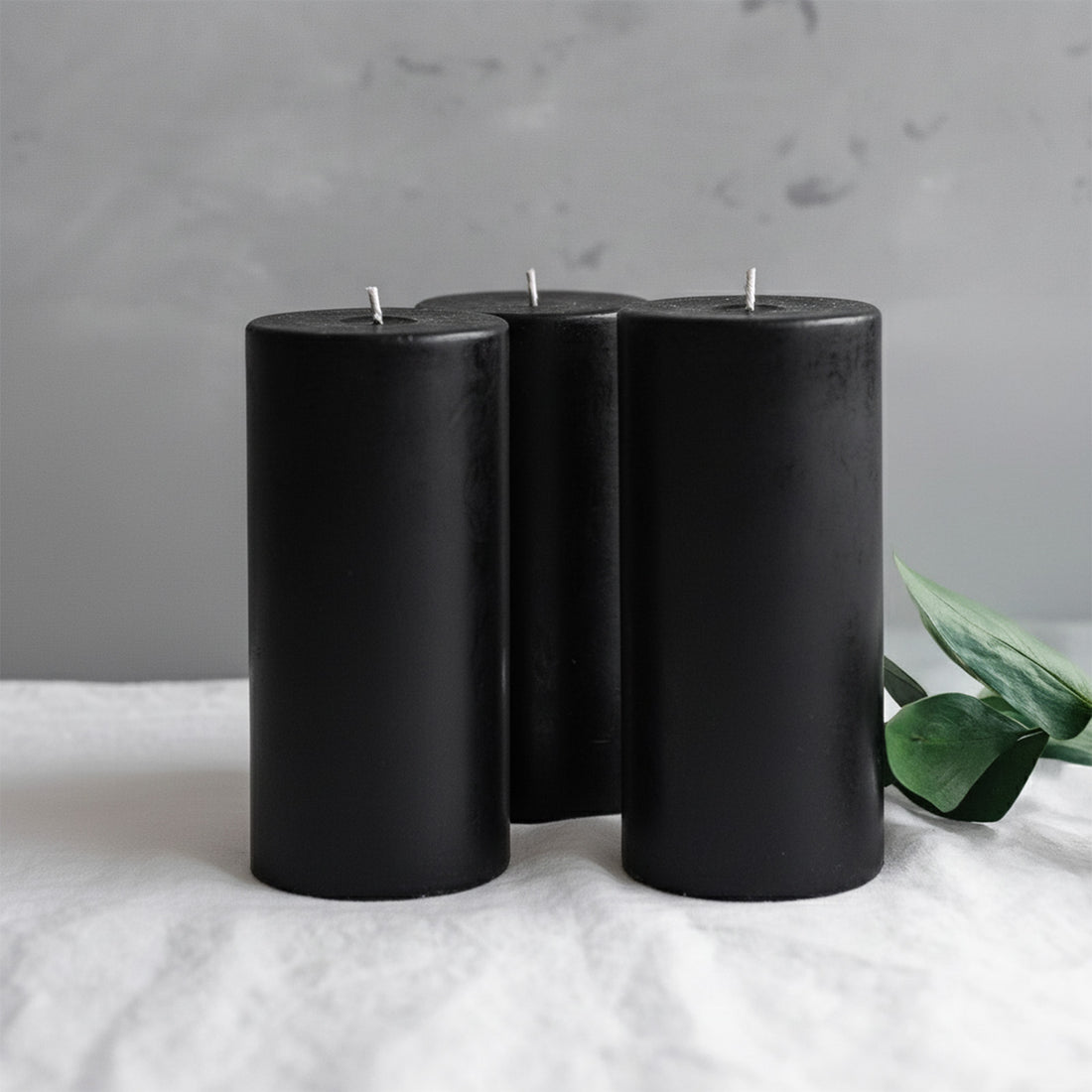 Black pillar candles grouped with greenery