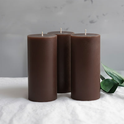 Set of three dark brown cylindrical candles with green foliage