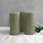 Three green pillar candles with a leaf accent on a soft surface.