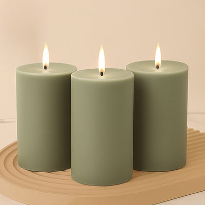 Green pillar candles with flames on a decorative tray.