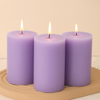Three lavender candles with flames on a wooden tray.