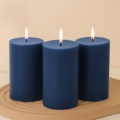 Set of three navy blue candles with flames, arranged on a wooden tray.